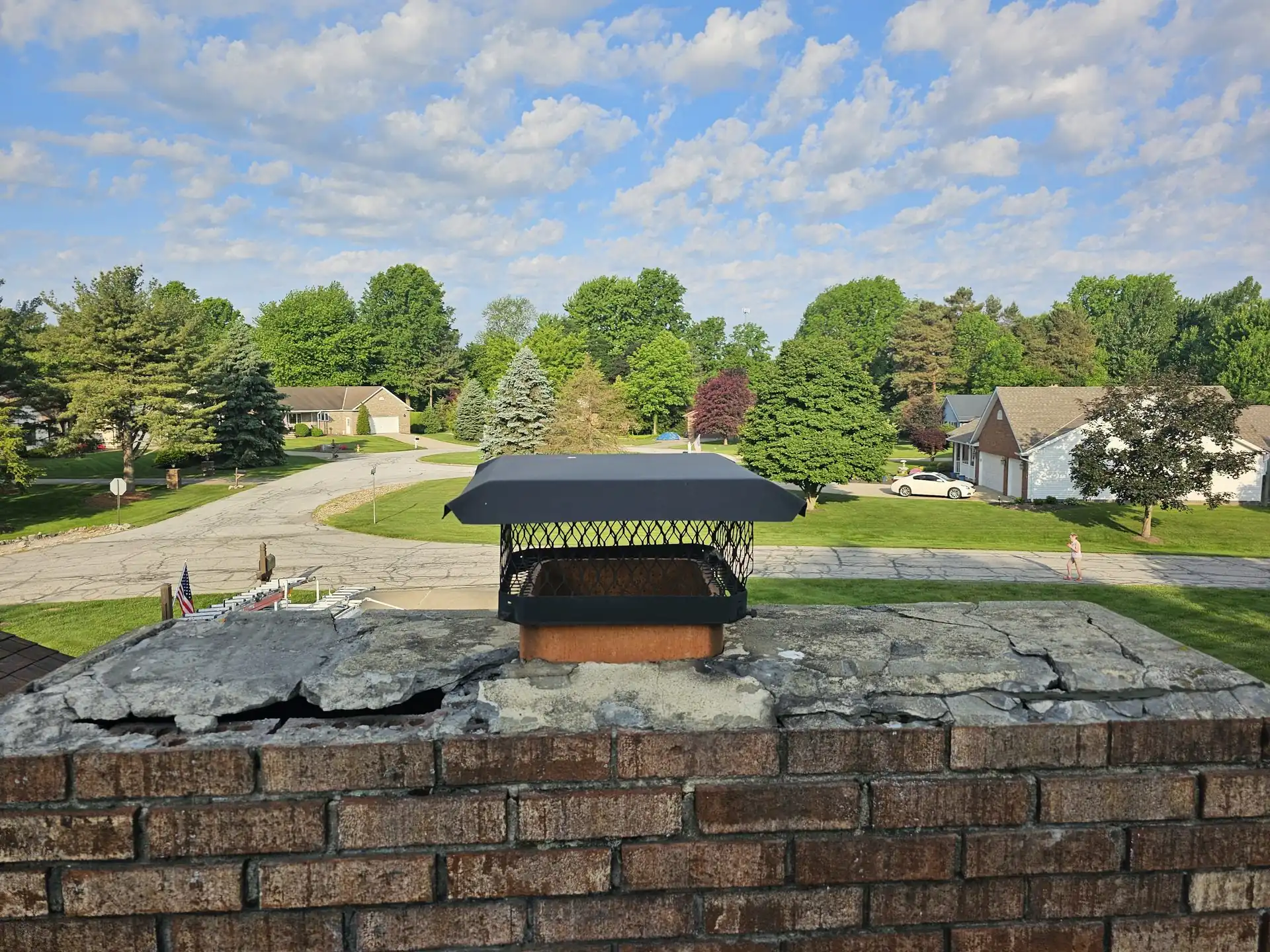 Green and Clean technician sweeping a chimney from the roof, van below